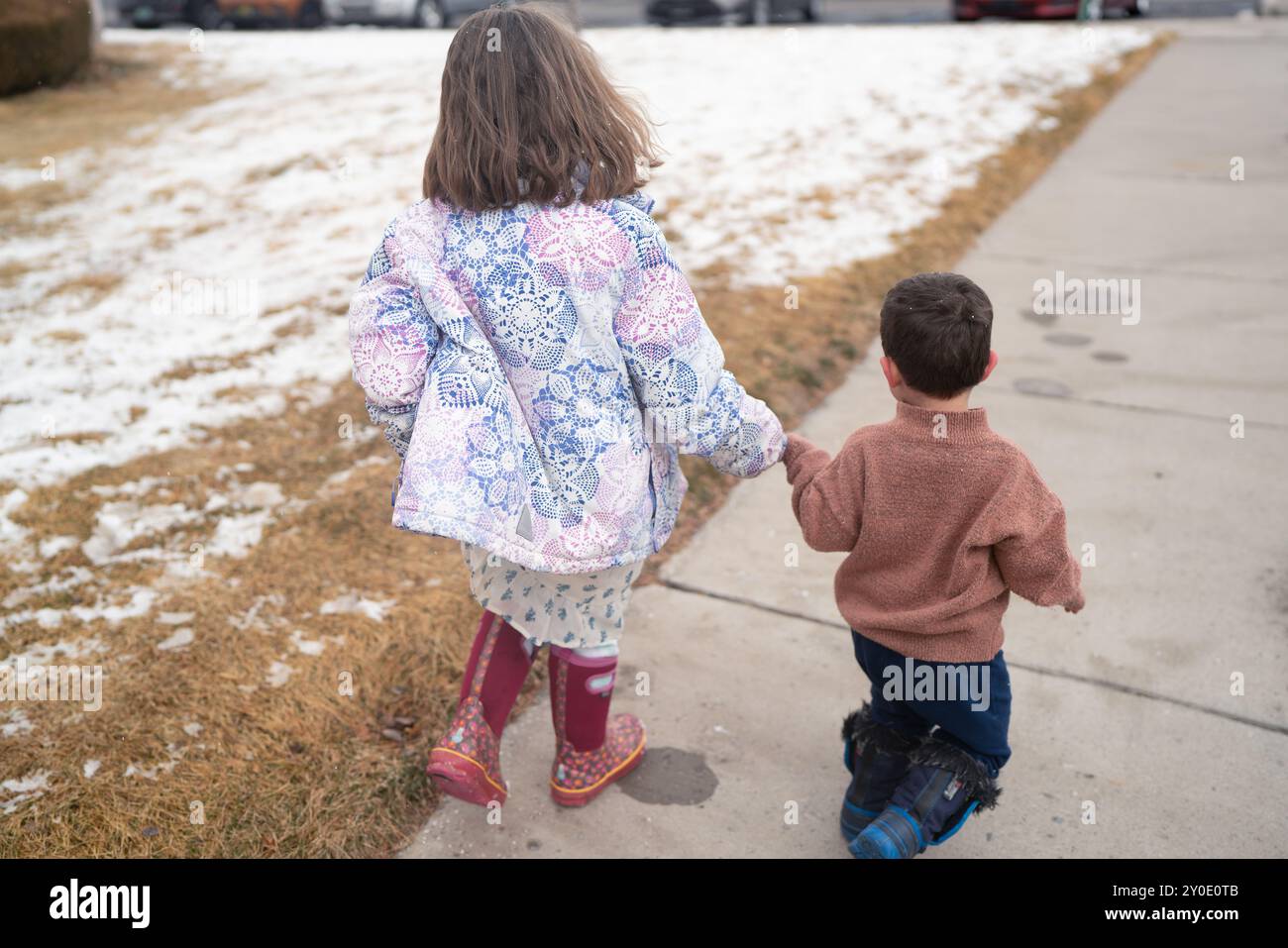 Fratelli che tengono per mano una passeggiata invernale Foto Stock