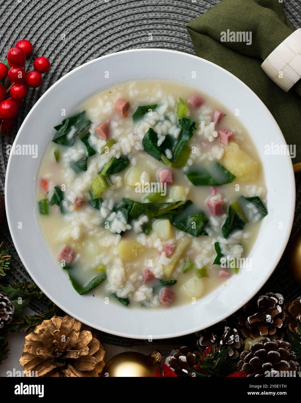 Zuppa di riso, prosciutto e spinaci, tapa spagnola tradizionale. Tavolo con vista dall'alto e decorazioni natalizie. Foto Stock