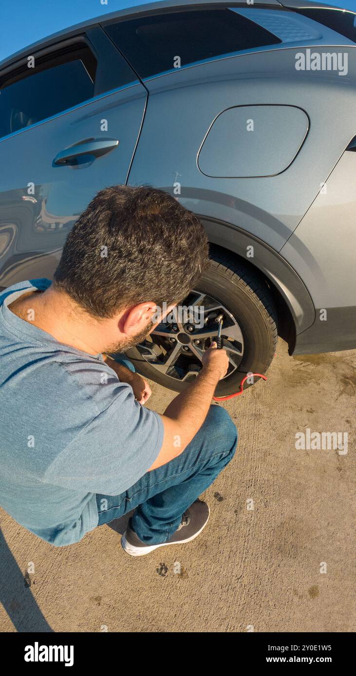 Un uomo sta lavorando su una gomma per auto. Lo pneumatico è sgonfio e l'uomo sta cercando di ripararlo Foto Stock Un uomo sta lavorando su una gomma per auto. Lo pneumatico è sgonfio e l'uomo sta cercando di ripararlo Foto Stock
