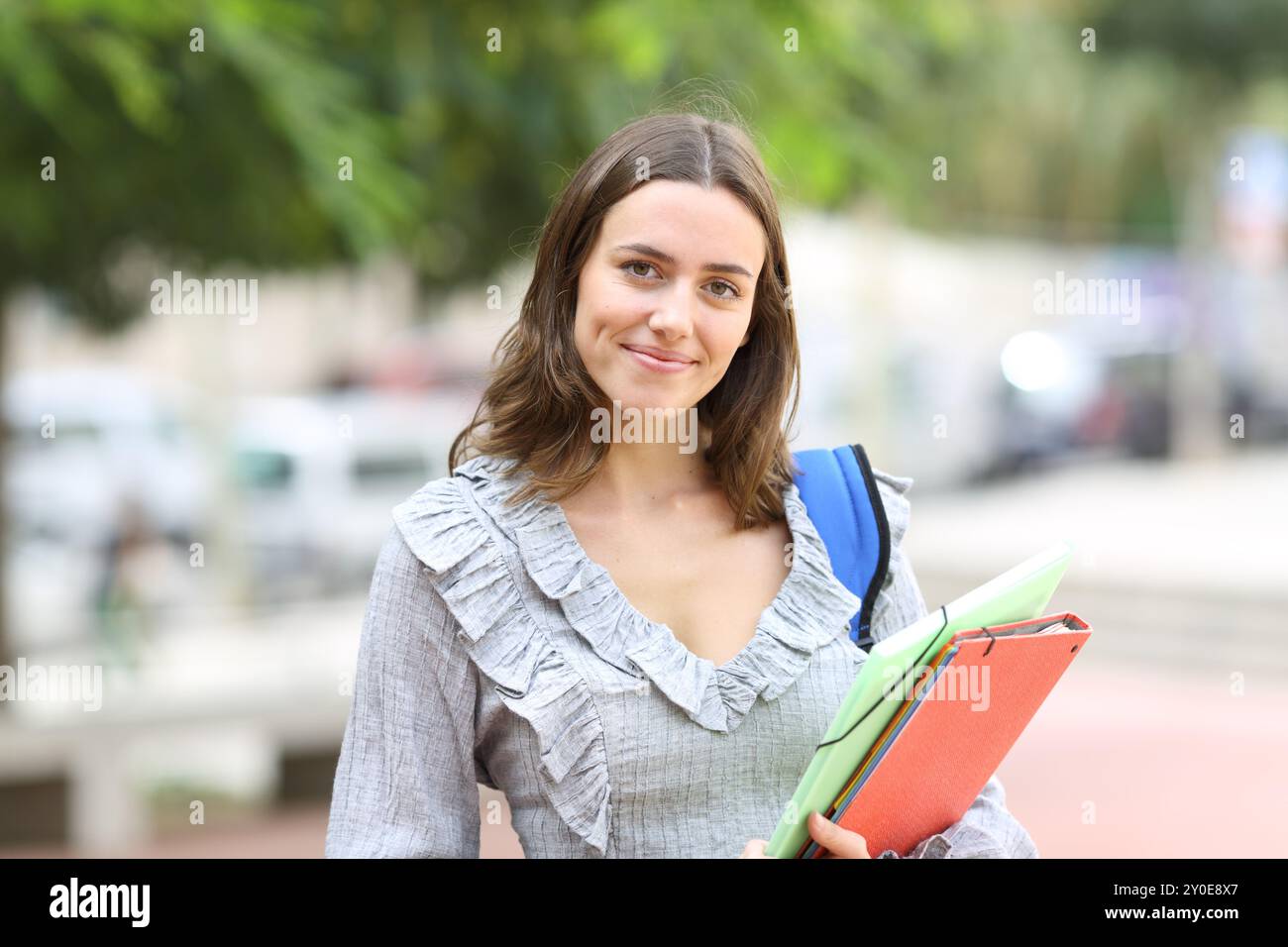 Studente soddisfatto che posa guardando la macchina fotografica in piedi per strada Foto Stock