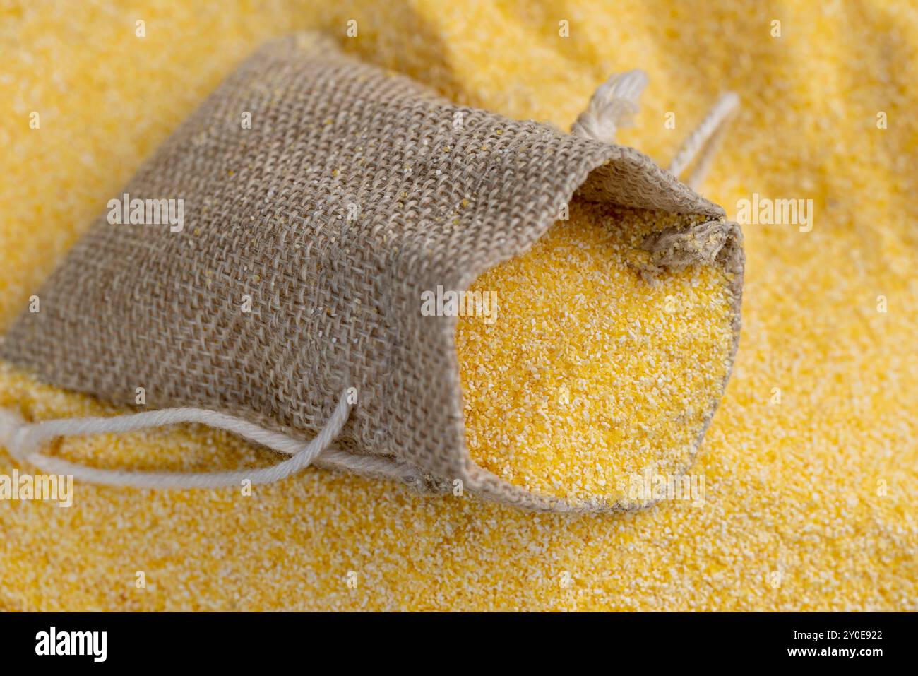 Farina di mais secca versata in un sacchetto di lino per la preparazione di farina di mais di alta qualità a partire da grani di mais in un sacchetto Foto Stock