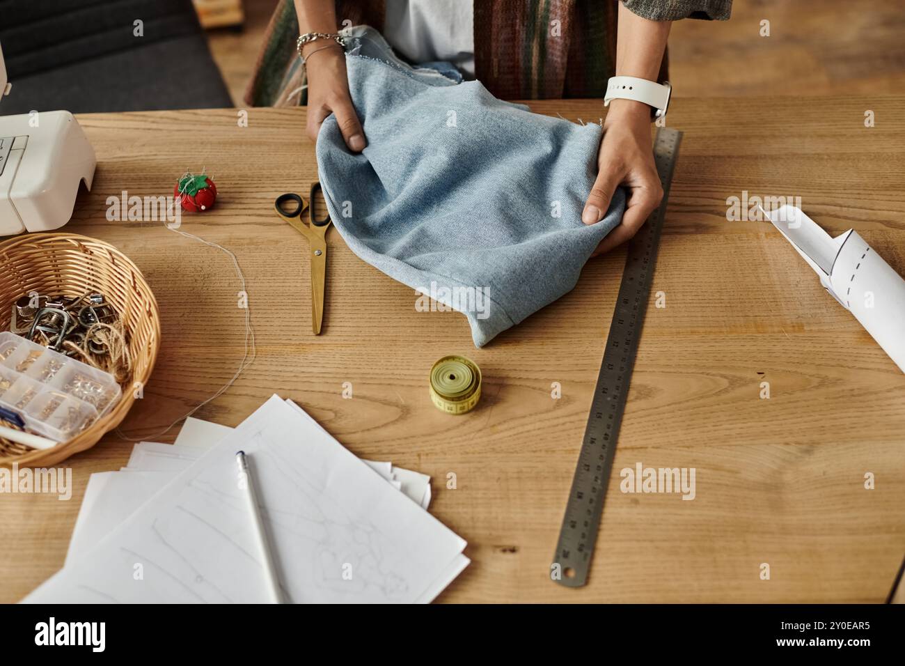 Una donna creativa trasforma i capi in nuovi stili nel suo vivace spazio di lavoro. Foto Stock