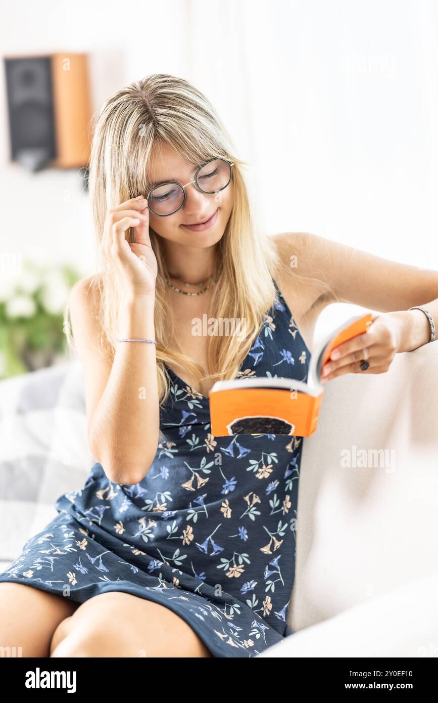 Una giovane signora sta leggendo un libro e indossa occhiali da vista. Foto Stock