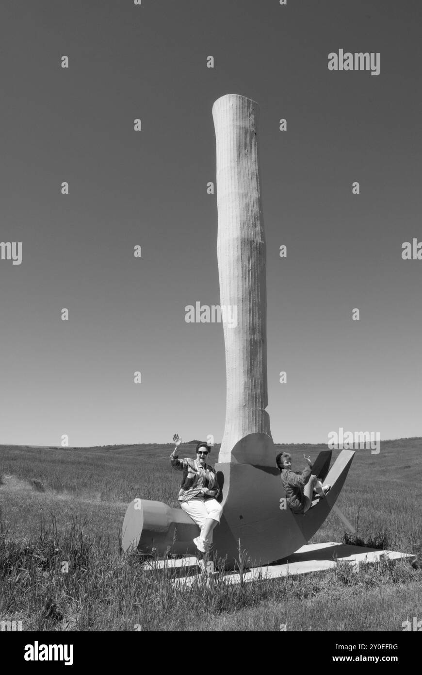 Due donne caucasiche, da 55 a 60 anni, sedute su una statua del martello da artiglio e divertirsi al Porter Sculpture Park di Montrose, South Dakota. Foto Stock