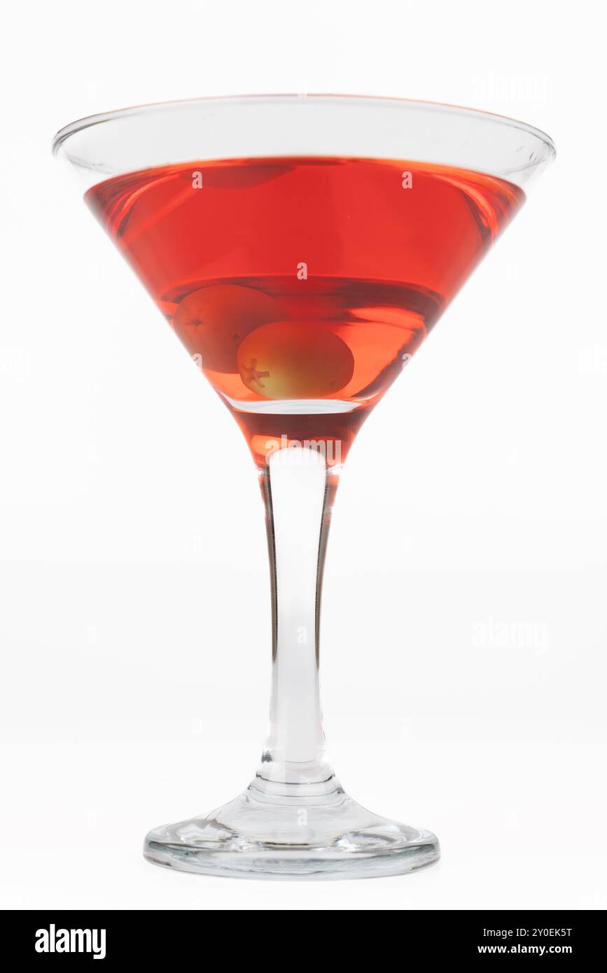 Un'immagine verticale che mostra un bicchiere da cocktail contenente una bevanda rossa e due olive. Posizionato a sinistra su uno sfondo bianco semplice, il ph Foto Stock