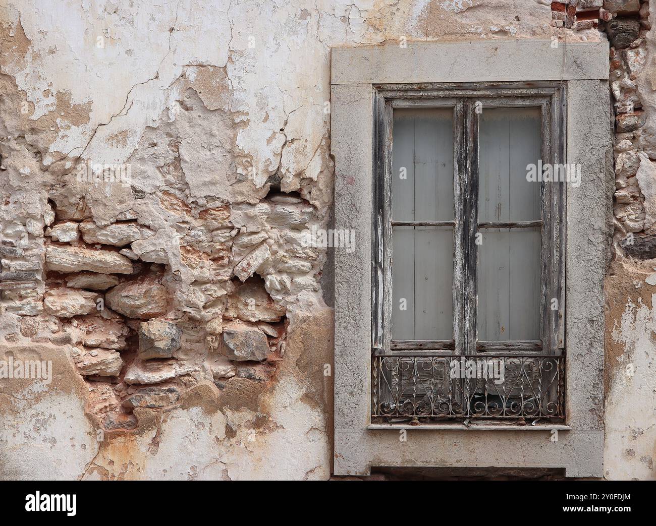 Vecchio muro di pietra danneggiato bianco con intonaco rovinato e finestra vintage Foto Stock