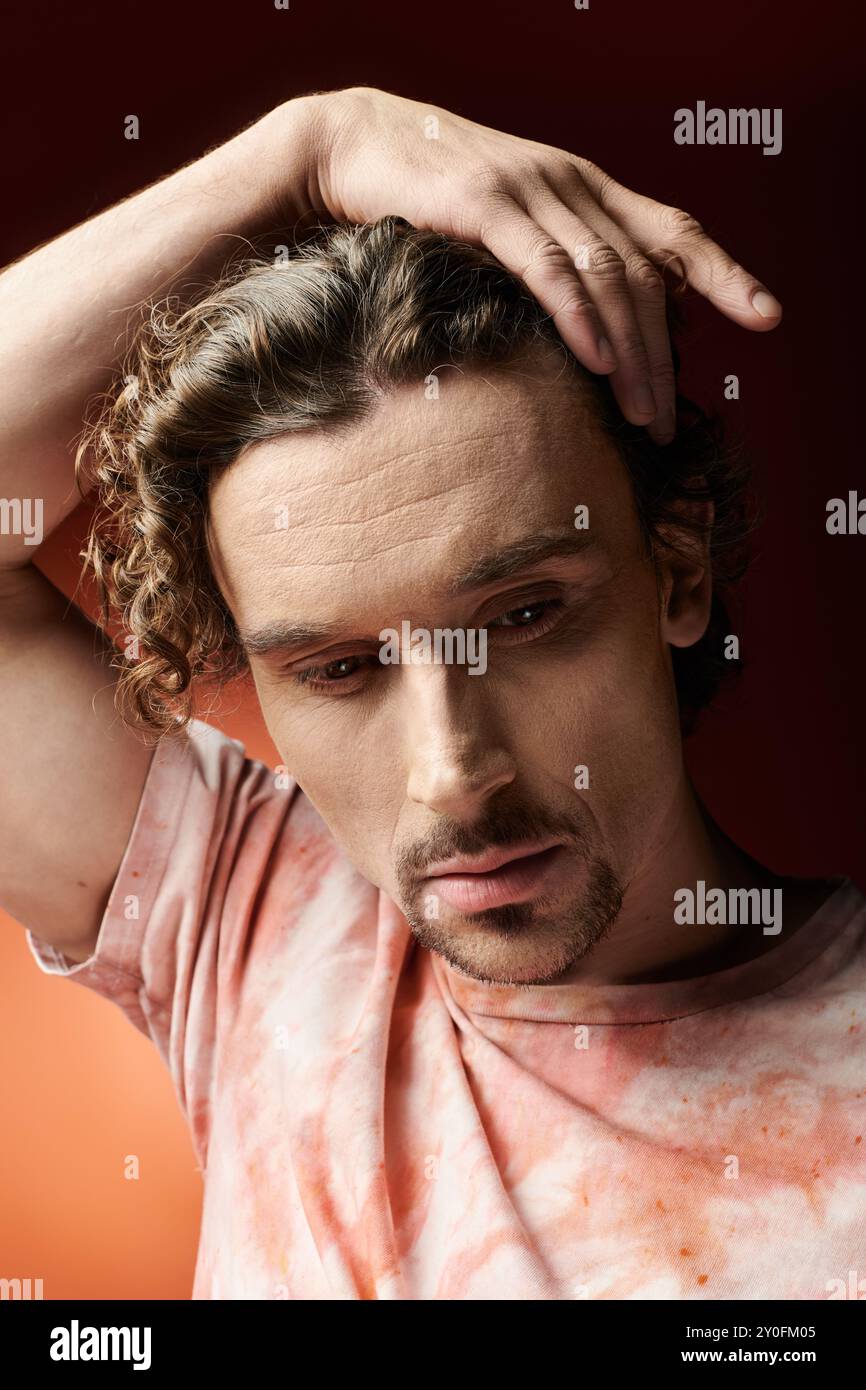 Un bell'uomo esprime emozioni profonde su uno sfondo vivido. Foto Stock