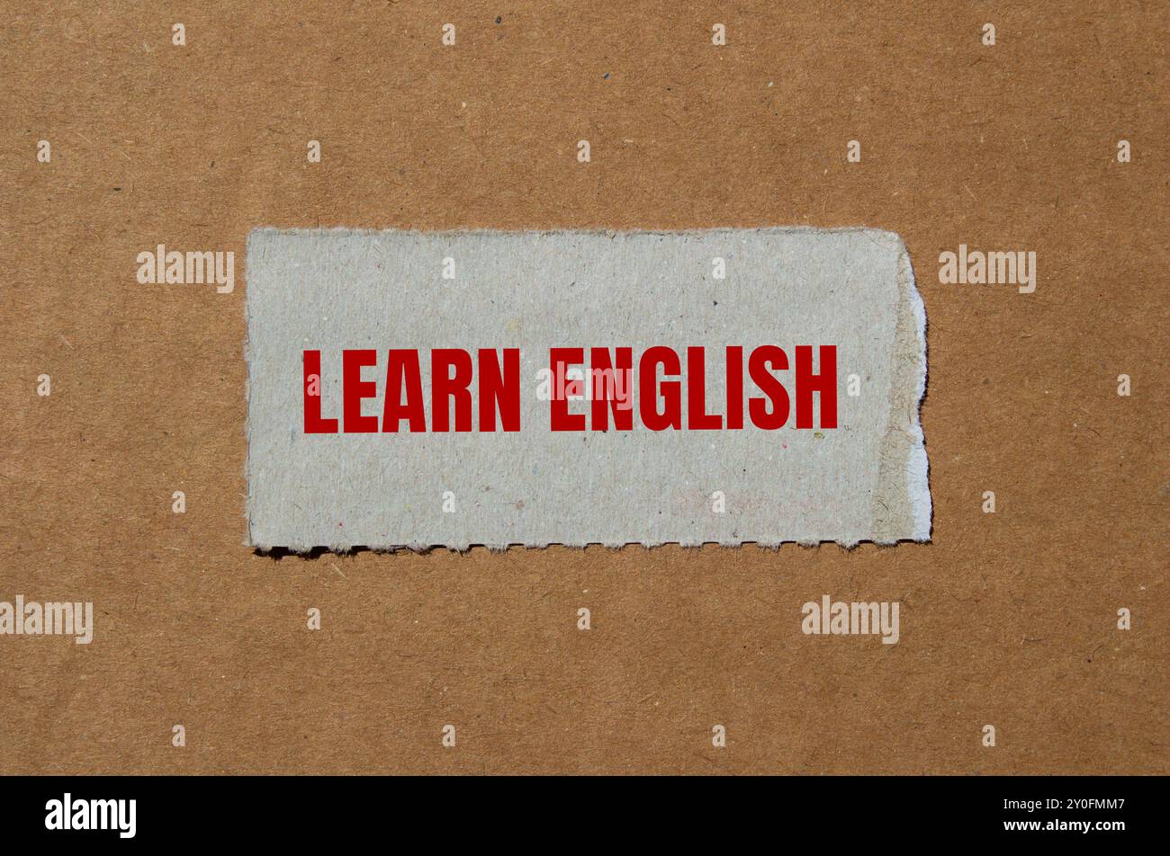 Impara il messaggio in inglese scritto su un pezzo di carta strappato con sfondo in cartone. Simbolo Impara l'inglese concettuale. Copia spazio. Foto Stock