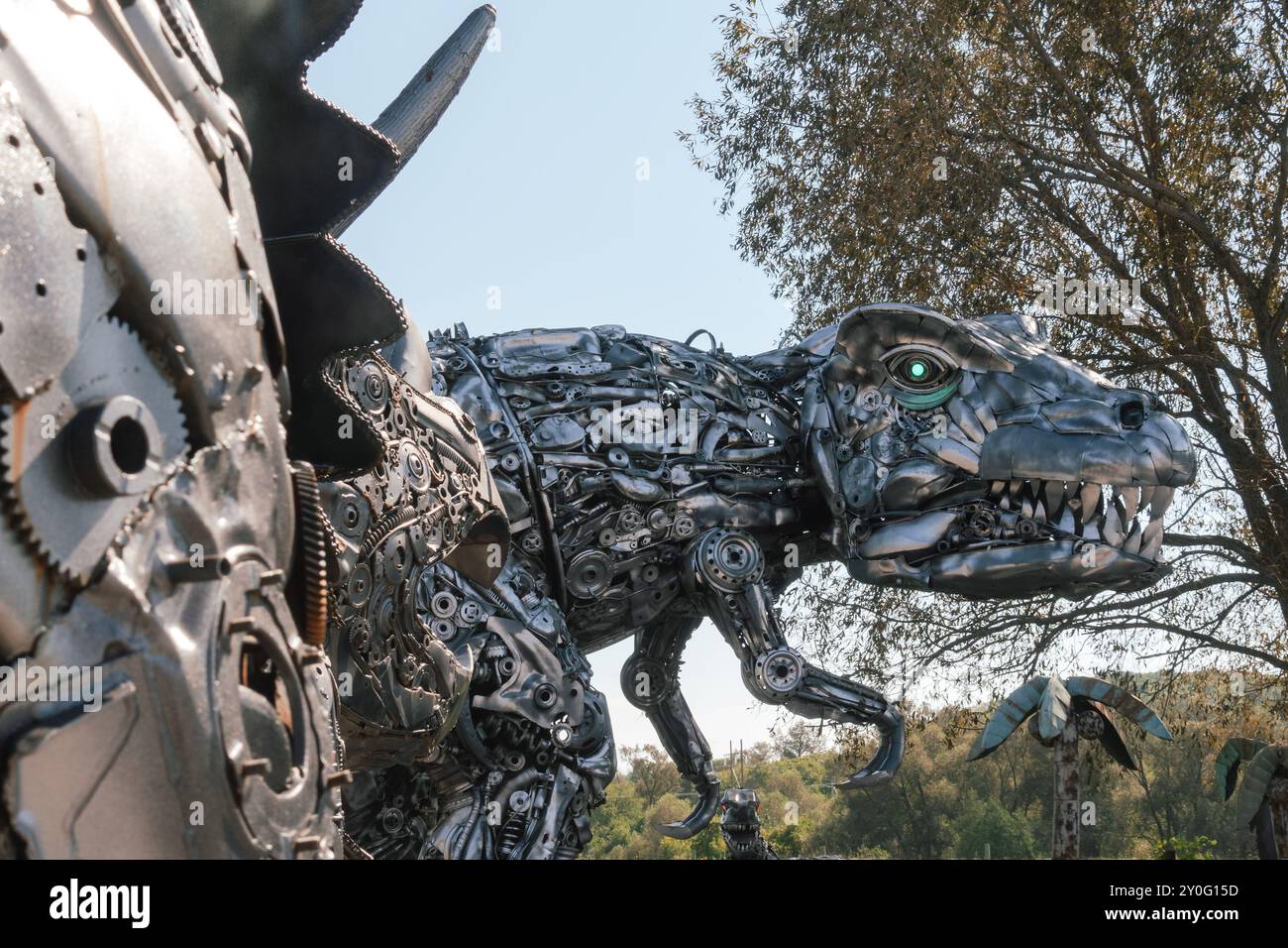 Una grande scultura di dinosauro in metallo, caratterizzata da dettagli intricati e una posa dinamica, che mostra il suo design artistico e la sua presenza imponente. Foto Stock