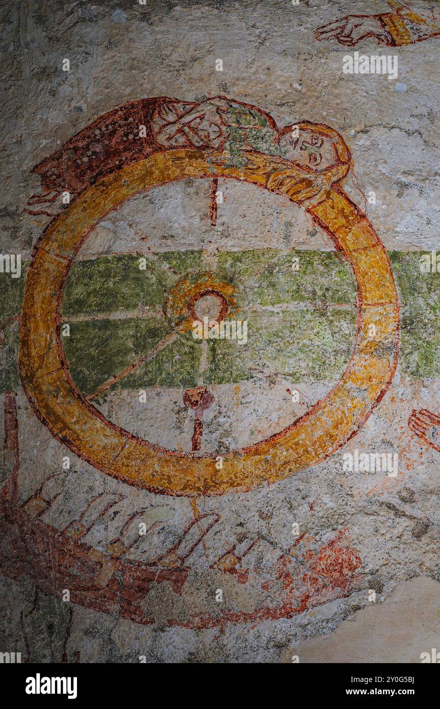 Mano di dio sopra e semicerchio di temibili coltelli sotto Santa Caterina d'Alessandria mentre giace su una ruota in rottura. Affresco medievale, Abbazia di Piona, Colico, Lombardia, Italia. L'affresco è insolito in quanto Santa Caterina è più frequentemente raffigurata in piedi trionfante con la ruota distrutta. Foto Stock