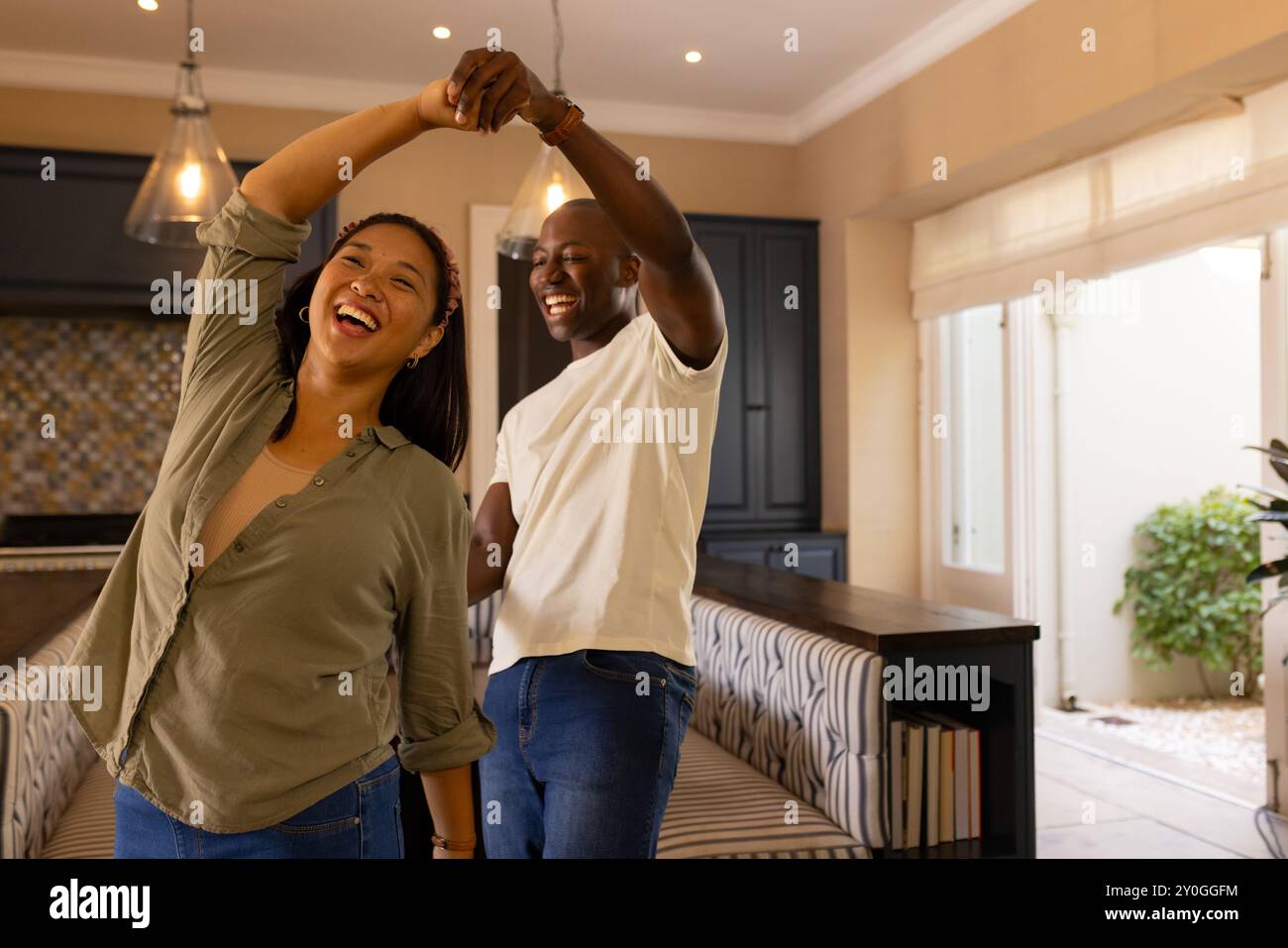 Ballare insieme, una felice coppia multirazziale che si diverte a trascorrere momenti di qualità nella moderna cucina casalinga Foto Stock