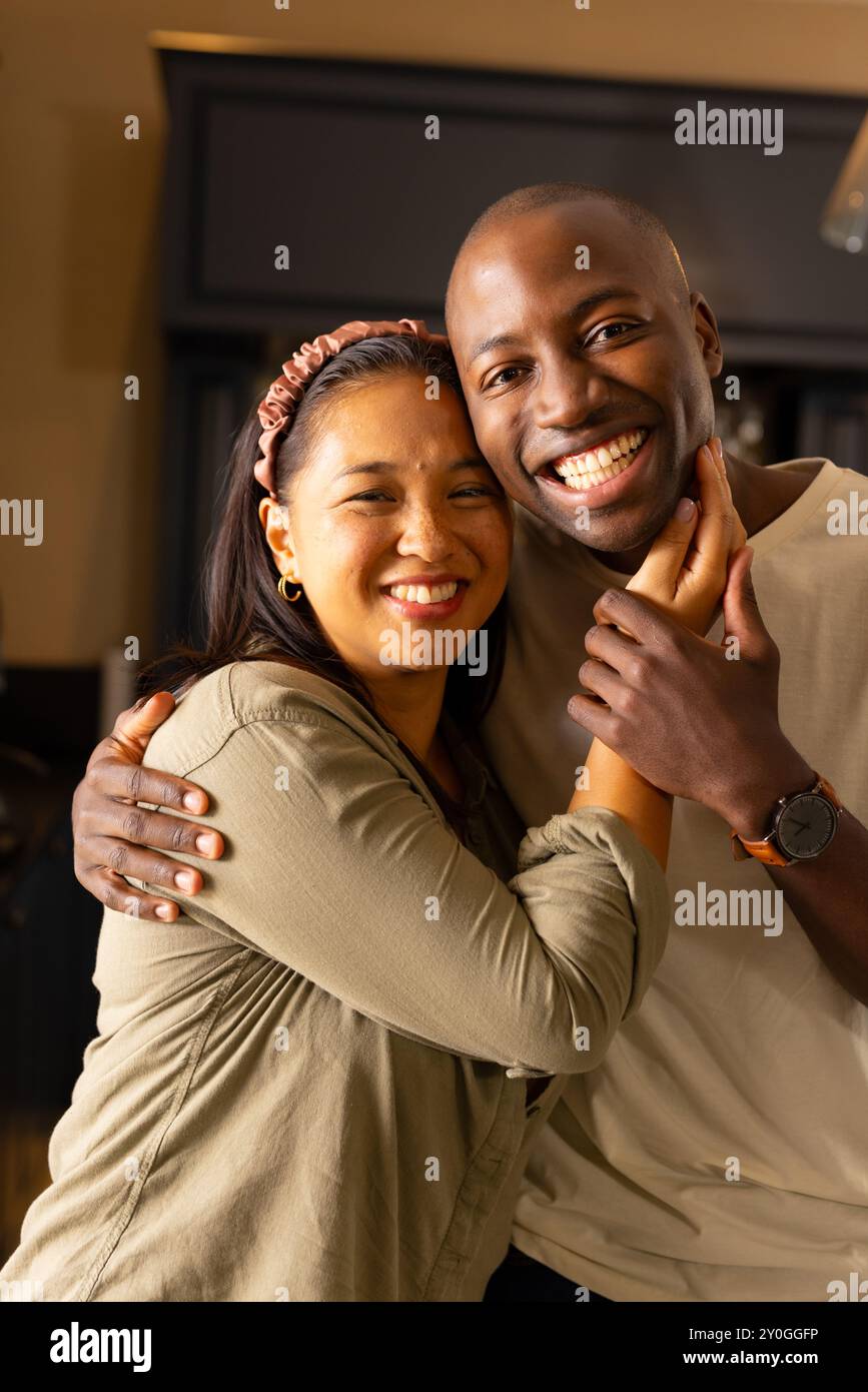 Una coppia multirazziale sorridente che si abbraccia a vicenda, godendo di momenti di qualità a casa Foto Stock