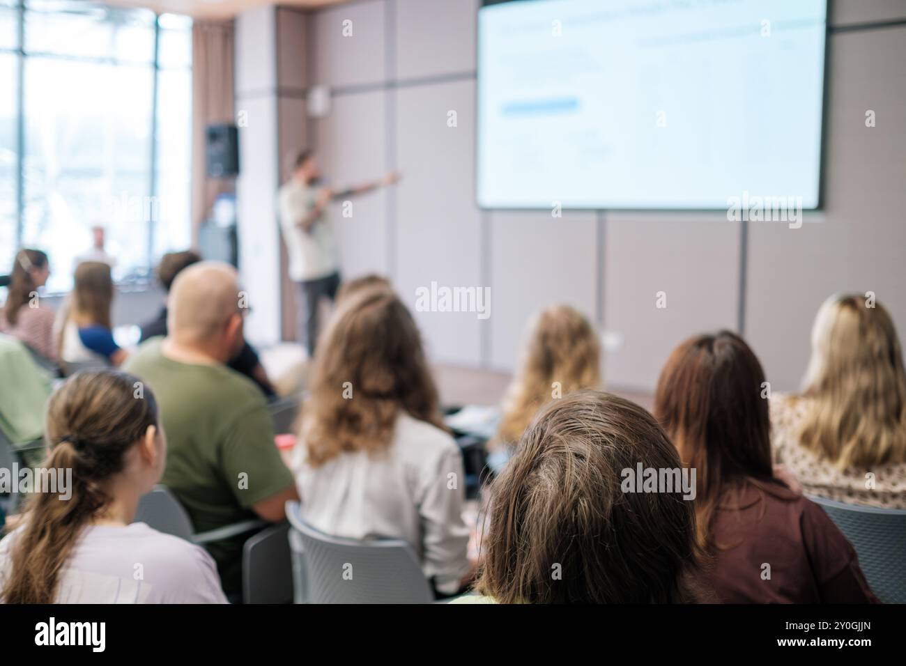 Immagine sfocata della presentazione aziendale con il pubblico seduto in una moderna sala conferenze, concentrandosi sull'apprendimento e la collaborazione Foto Stock