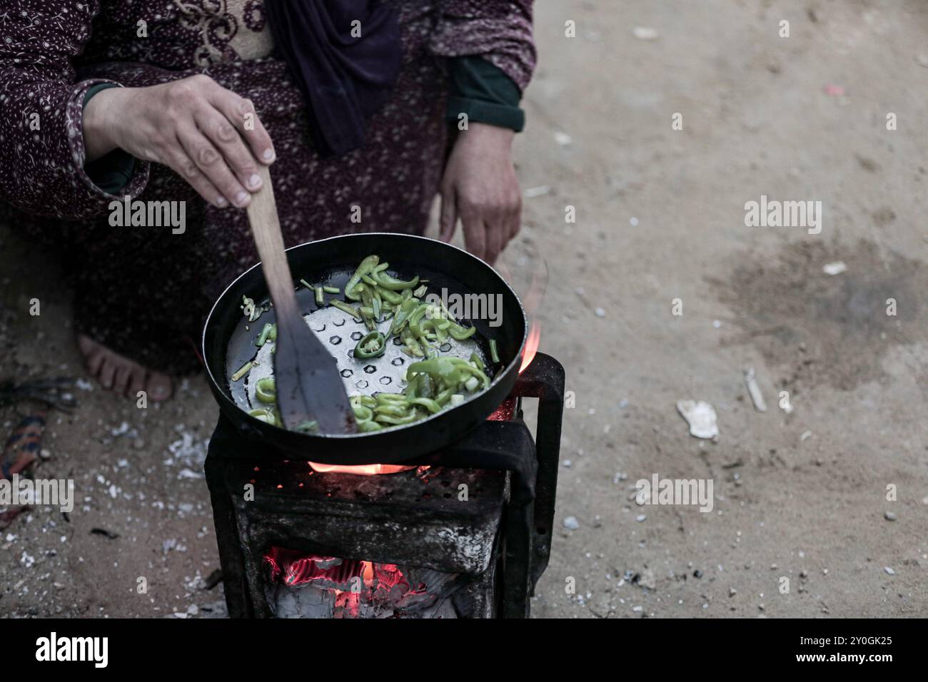 Gaza, Palestina. 13 marzo 2024. I palestinesi sfollati cucinano cibo molto basilare fuori dalle loro tende intorno all'ospedale Shuhada al-Aqsa a Deir al-Balah, nella zona centrale della Striscia di Gaza. La terribile situazione a Gaza continua senza sosta in mezzo agli scioperi israeliani e quasi nessun aiuto umanitario è consentito nell'enclave palestinese devastata dalla guerra. Secondo il ministero della salute di Gaza, 27 persone, la maggior parte dei quali bambini, sono morte per malnutrizione e disidratazione, con il trattamento della carestia in costante aumento Foto Stock