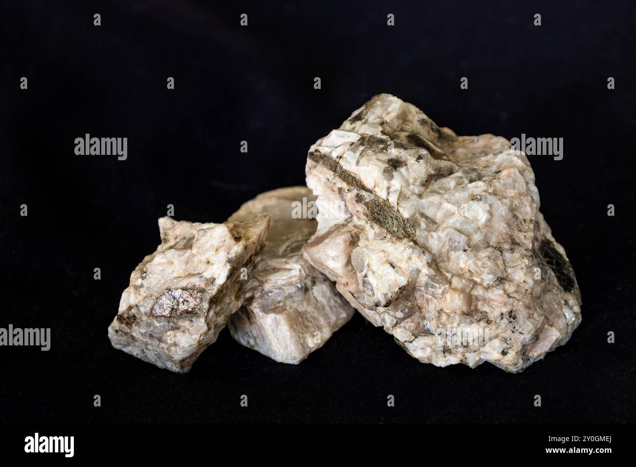 Campioni di pegmatite granitica costituita prevalentemente da feldspato plagioclasio e biotite su sfondo nero. Foto Stock