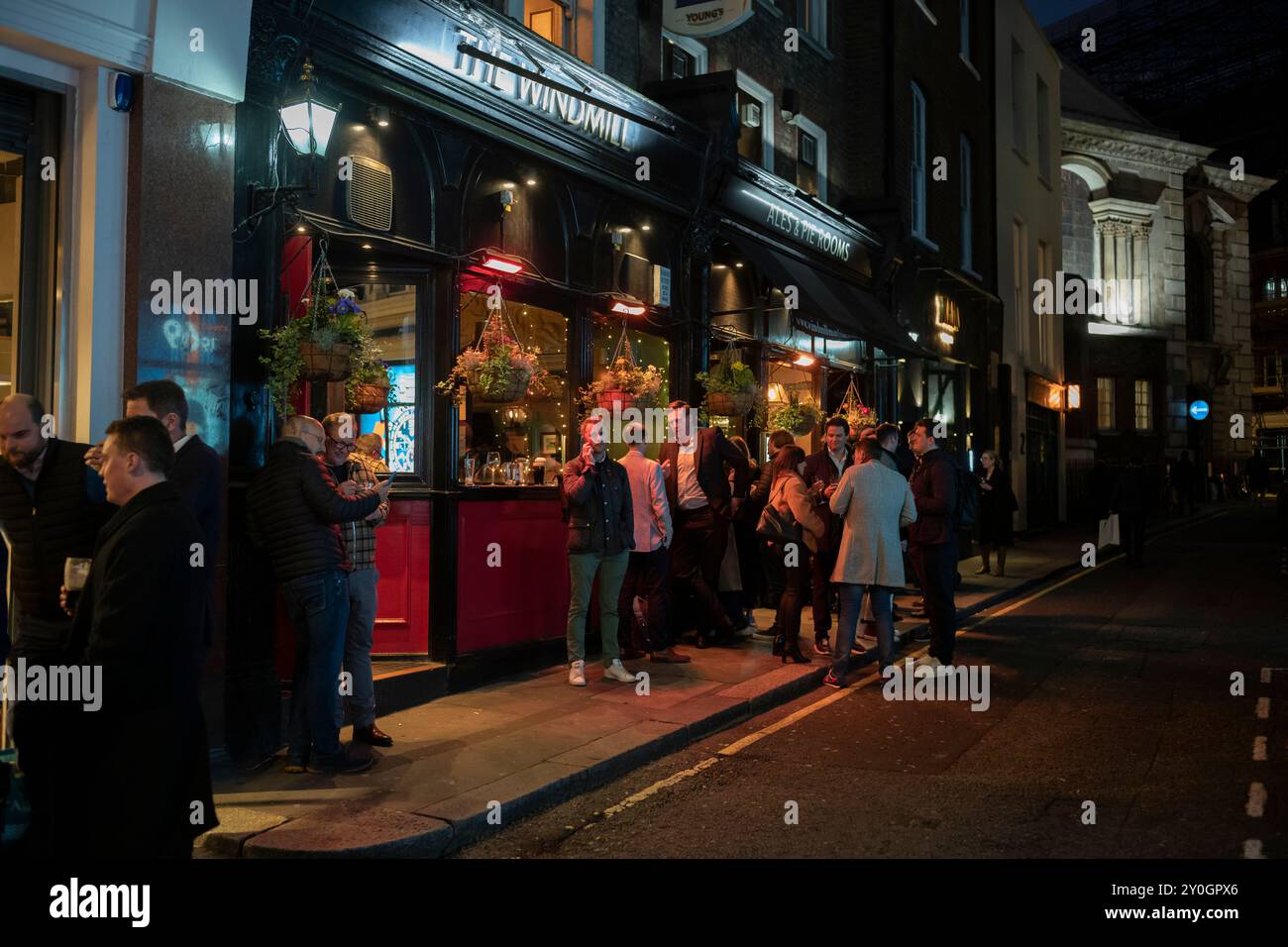 I bevitori della città si riuniscono fuori dal pub Windmill, in Mill Street, situato nel cuore di Mayfair, nel centro di Londra, Inghilterra, Regno Unito Foto Stock