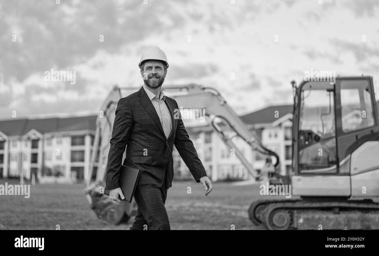 foto di un uomo d'affari con un piano di costruzione che indossa un cappello duro e uno striscione. Foto Stock