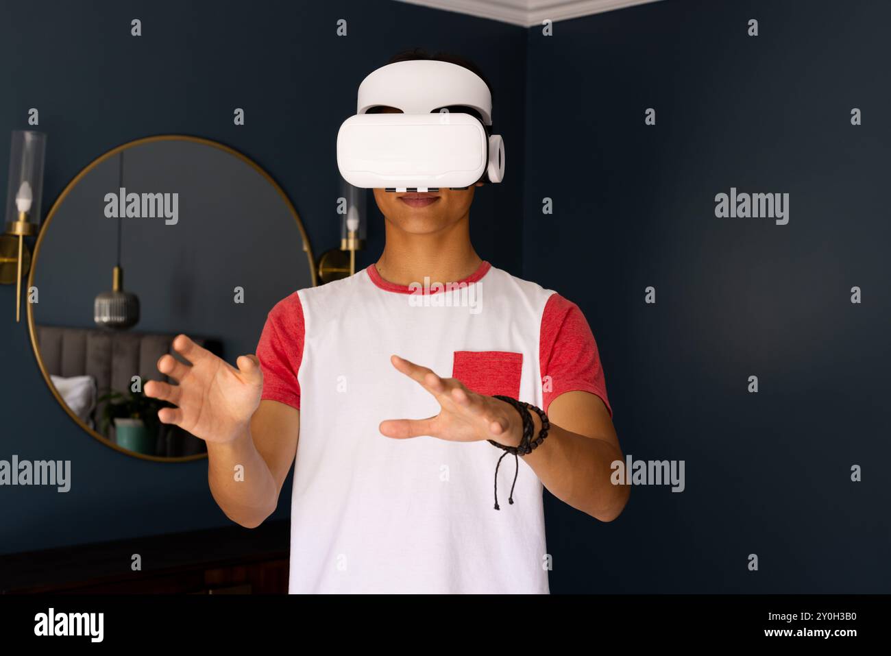 Utilizzando il visore VR, l'uomo asiatico interagisce con l'ambiente virtuale nella casa moderna Foto Stock