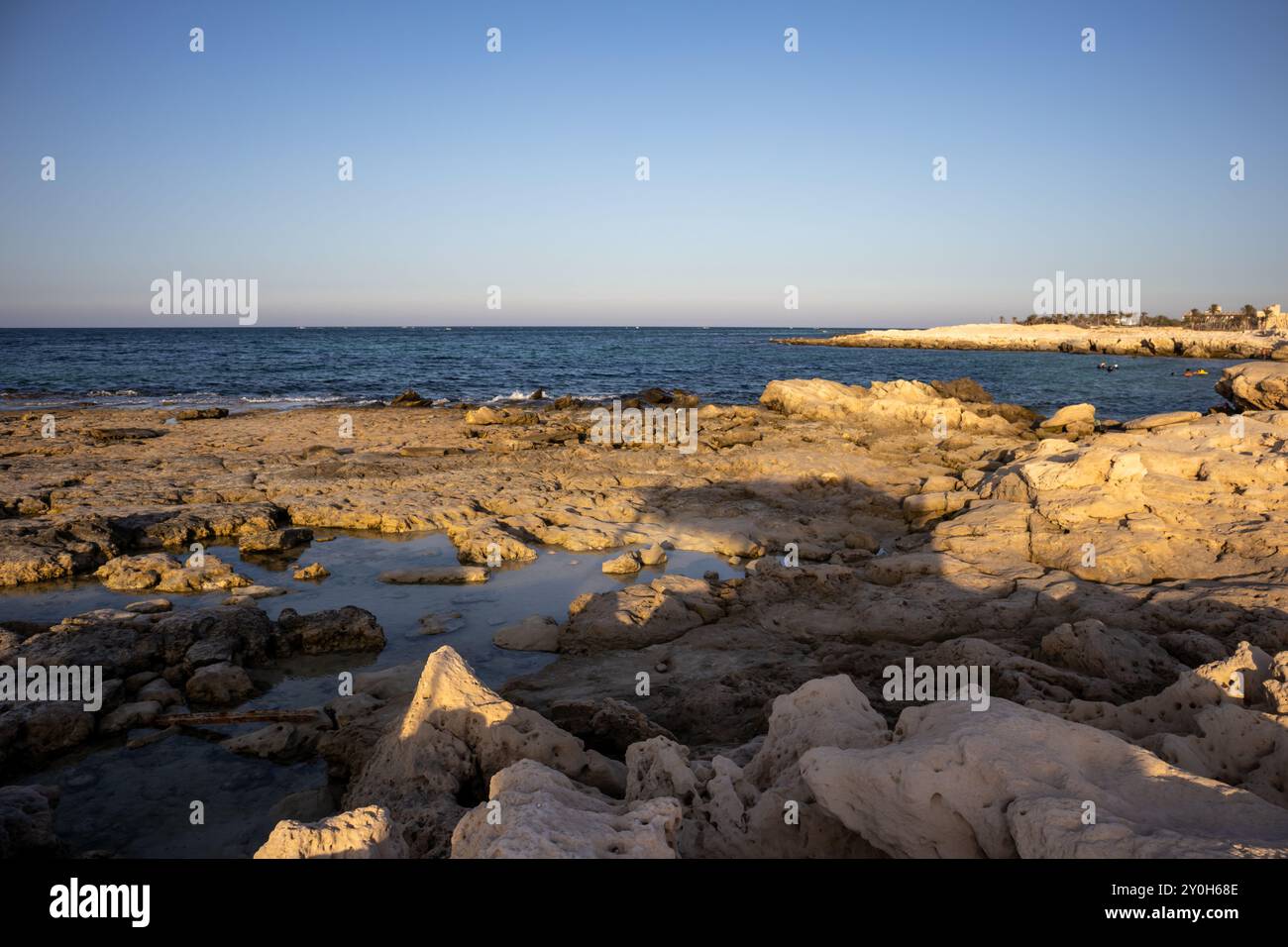 Costa rocciosa del Mediterraneo. Parte pubblica di una spiaggia. Rocce alla luce dell'ora d'oro. Djerba, Tunisia, Africa. Foto Stock