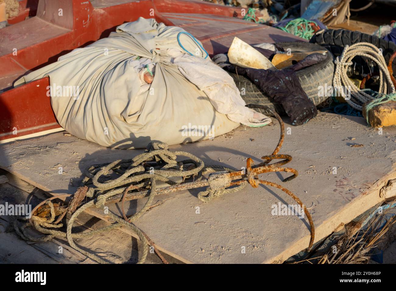 Natura morta con varie attrezzature per la pesca. Vecchia ancora arrugginita con corda, pacco, pneumatico, tutto alla luce dell'ora d'oro. Djerba, Tunisia, Africa. Foto Stock