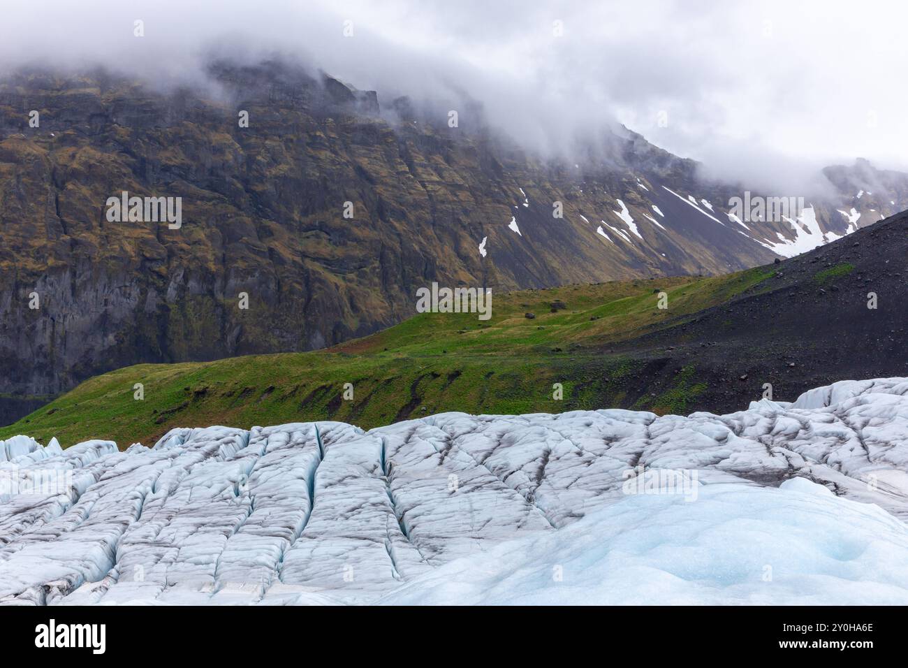 Paesaggio montano con il ghiacciaio Skaftafell in ritirata nel Parco Nazionale Vatnajokull, Islanda. Ghiacciaio blu con praterie verdi sullo sfondo. Foto Stock