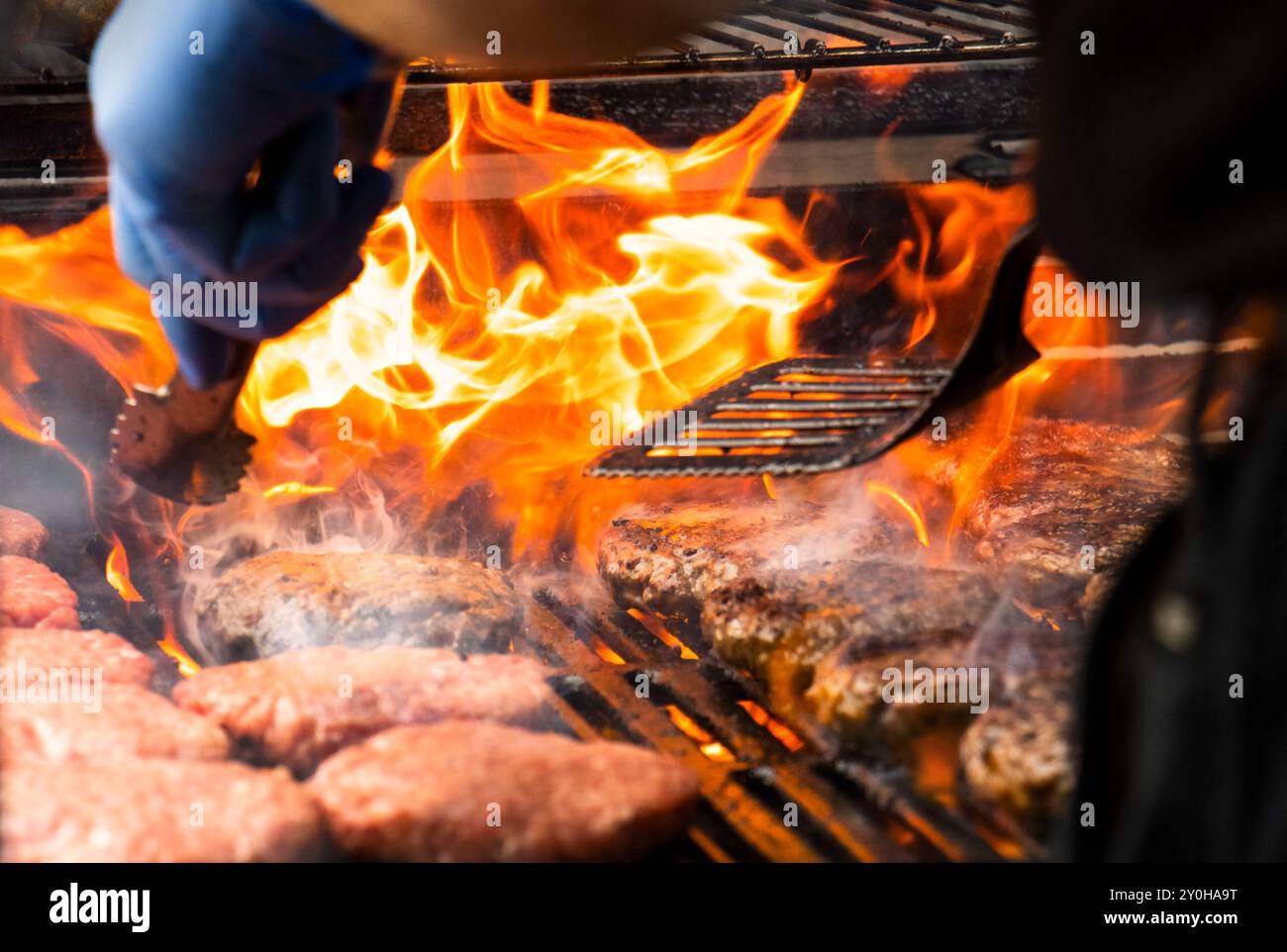 Cucinare hamburger su grill caldo con fiamme - hamburger grigliati alla fiamma. Gli hamburger sono un tradizionale barbecue estivo. Foto Stock