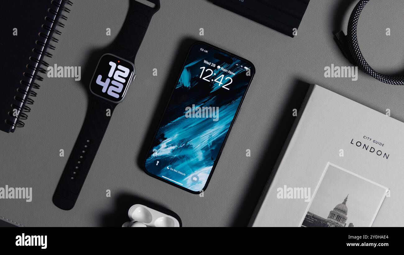 LONDRA - 28 AGOSTO 2024: Apple Watch con cinturino nero e iPhone sullo sfondo della scrivania Foto Stock