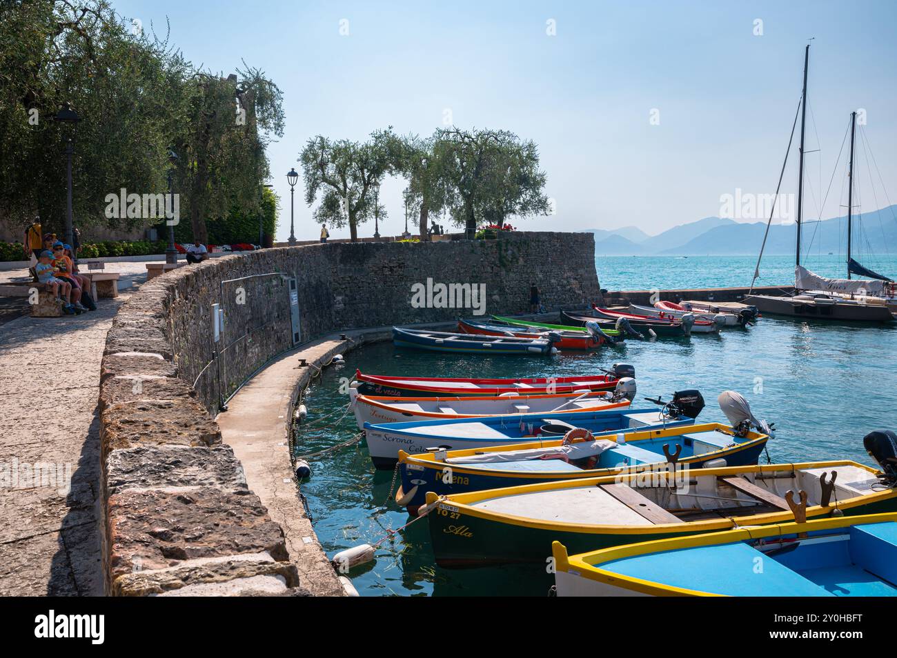 Pittoresca vista delle barche colorate nel porto di Torri del Benaco sulla sponda orientale del Lago di Garda, Italia Foto Stock