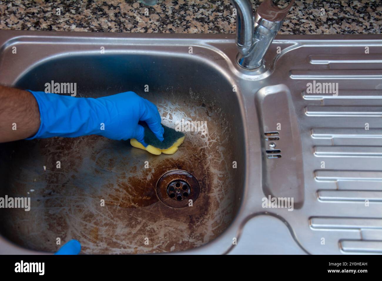 Pulizia ravvicinata del lavandino sporco in cucina strofinandolo con una spugna Foto Stock