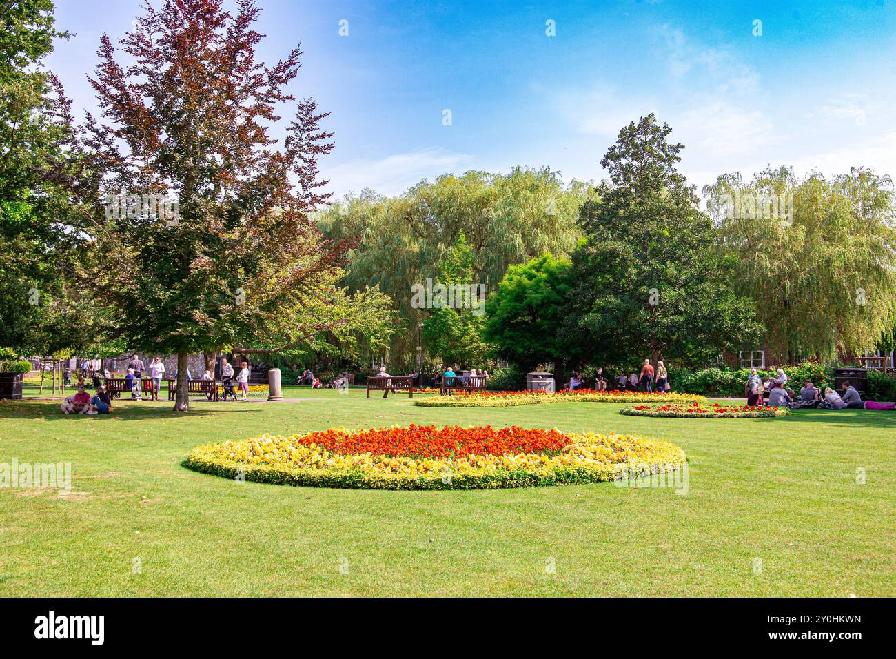 Un paesaggio panoramico del parco in una giornata di sole caratterizzato da aiuole fiorite, lussureggiante erba verde e numerose persone che si divertono ad attività ricreative. Winchester Regno Unito Foto Stock