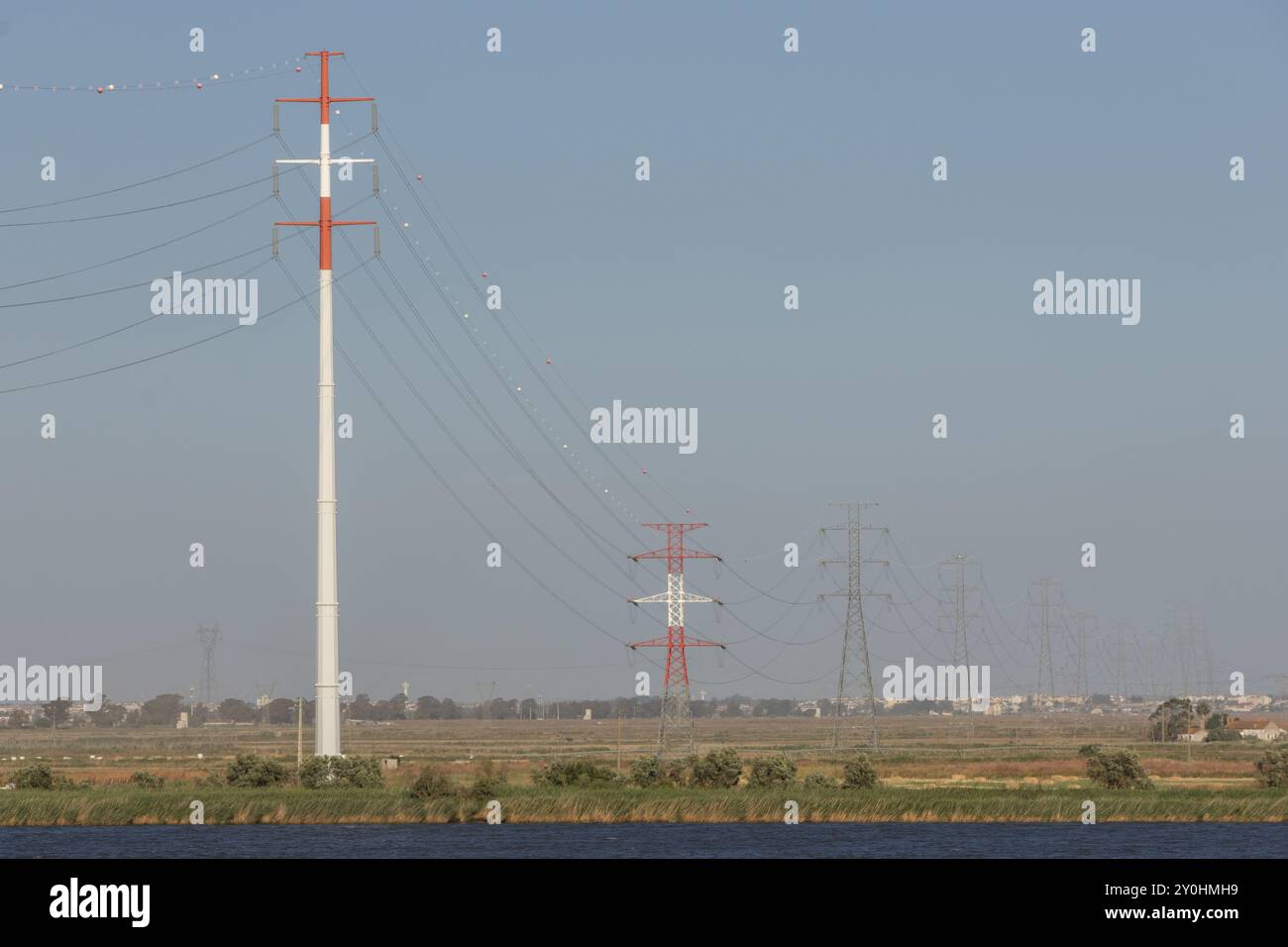 Alte linee elettriche metalliche che attraversano un paesaggio rurale, trasportano elettricità Foto Stock