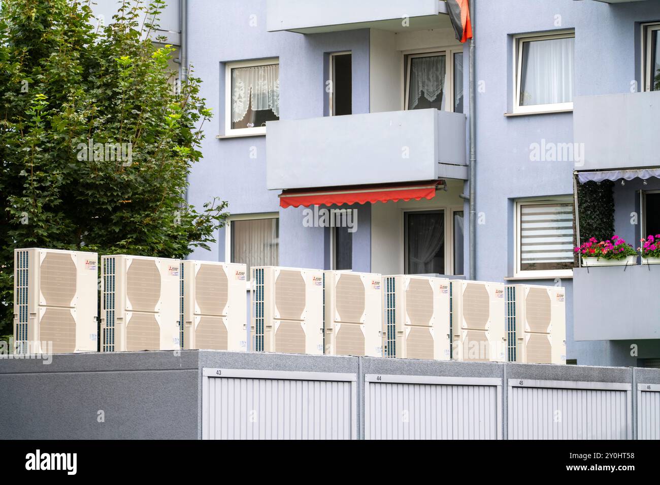 Pompe di calore in un'area residenziale, case multifamiliari sono alimentate con riscaldamento, raffreddamento e acqua calda domestica tramite questi dispositivi, montati su garage r Foto Stock