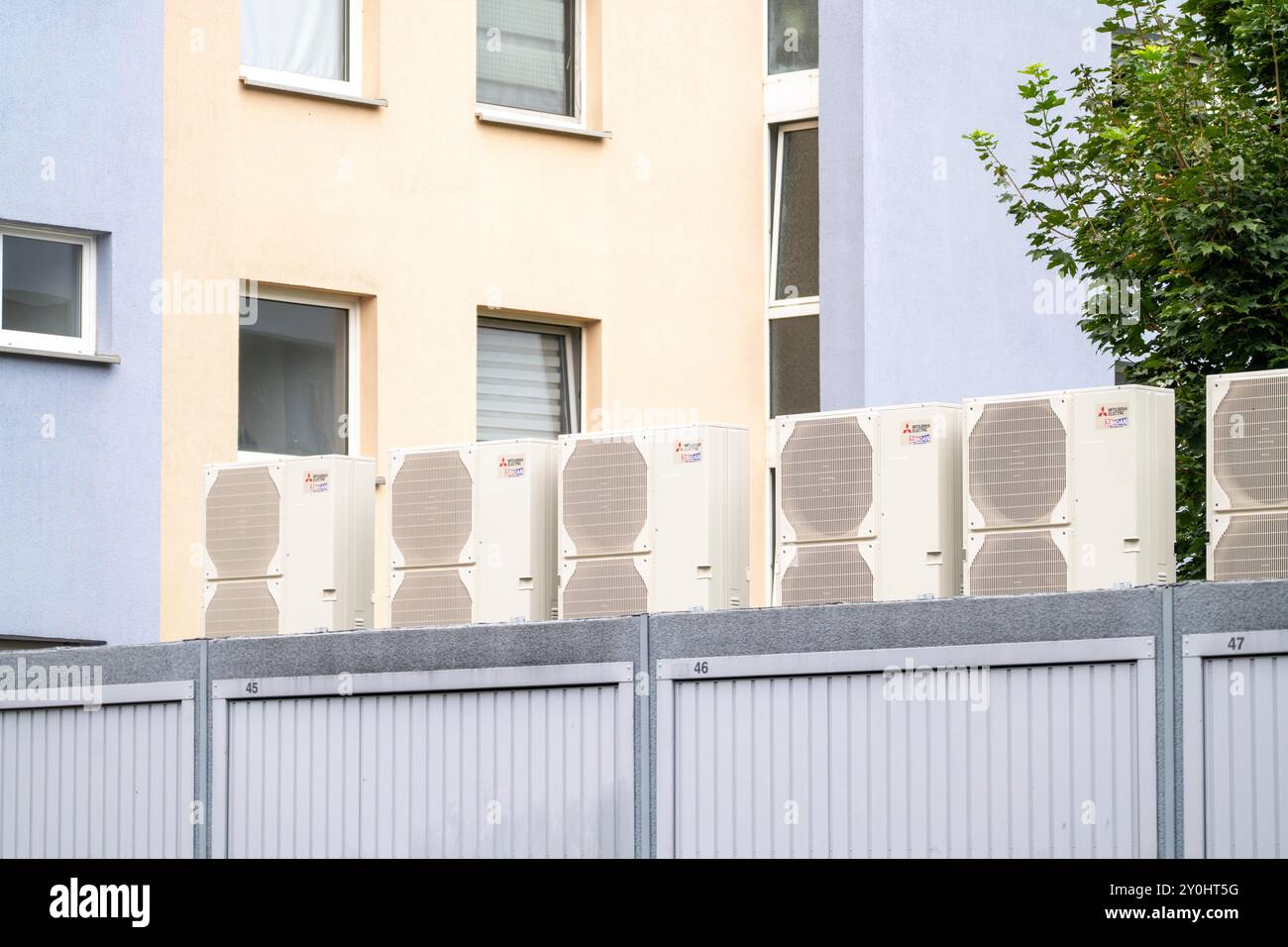 Pompe di calore in un'area residenziale, case multifamiliari sono alimentate con riscaldamento, raffreddamento e acqua calda domestica tramite questi dispositivi, montati su garage r Foto Stock