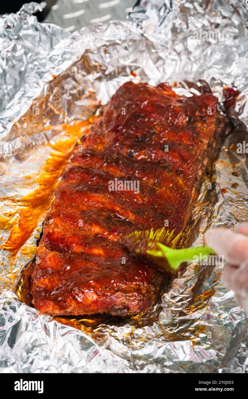 Un mercato agricolo del sabato mattina organizza una gara di barbecue sulla strada principale di Ellensburg, Washington, USA. Applicazione di salsa barbecue su una griglia di costolette. Foto Stock