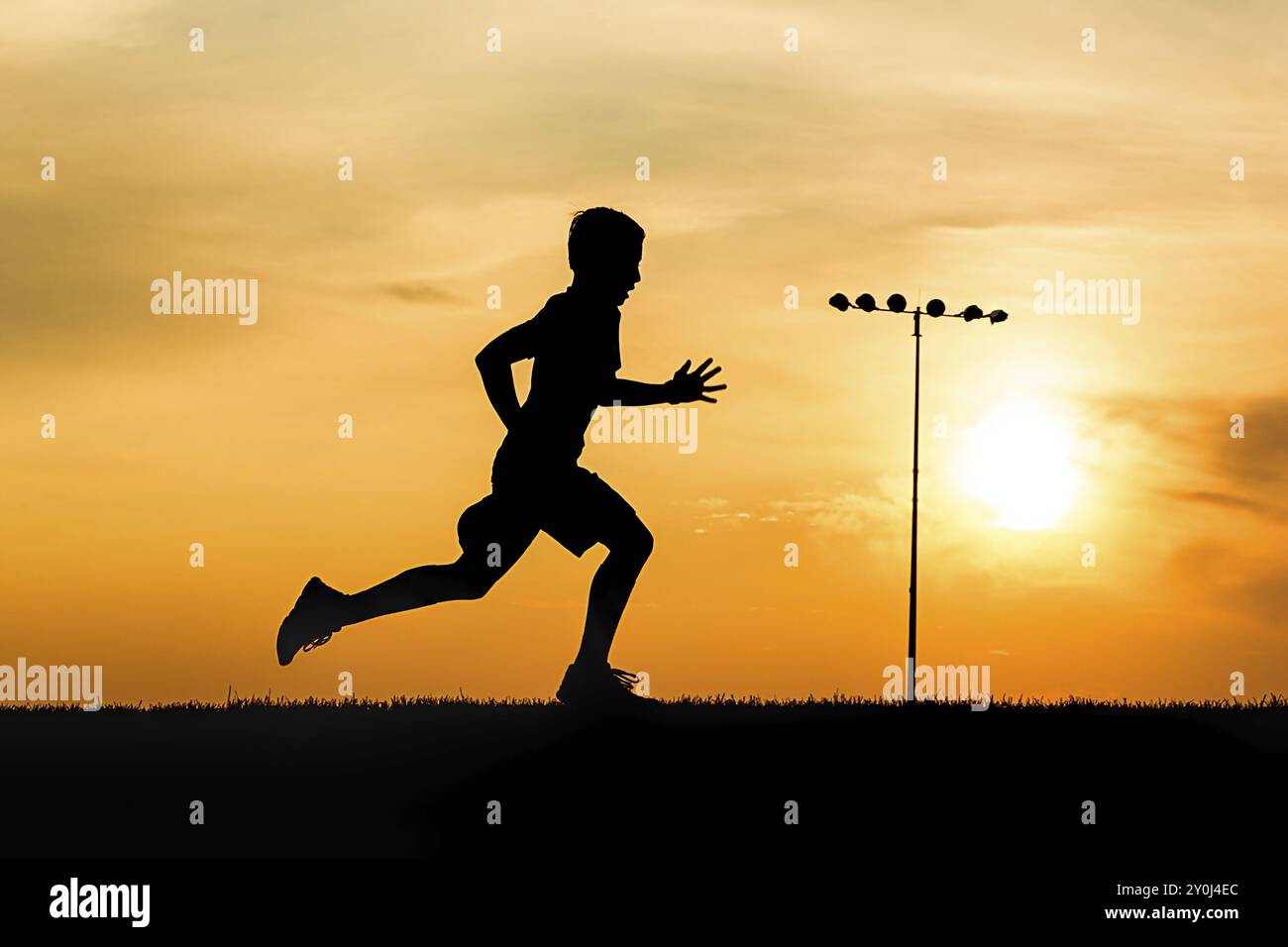 Un ragazzo atletico corre su un campo al tramonto nell'Idaho settentrionale Foto Stock