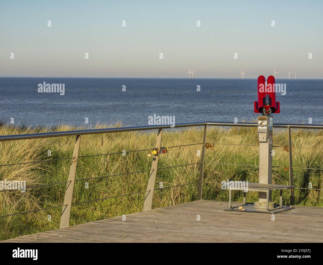 Un telescopio rosso su una piattaforma con vista sul mare e sulle turbine eoliche sullo sfondo, egmond aan zee, paesi bassi Foto Stock