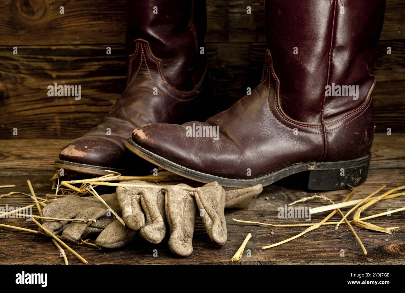 Un'immagine concettuale di stivali e guanti da cowboy indossati Foto Stock