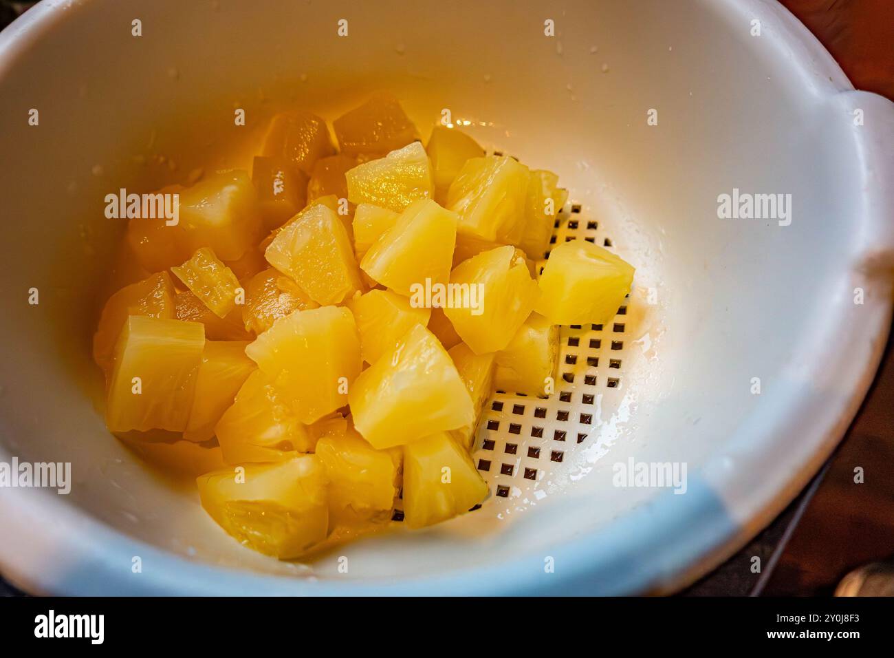 Pezzi di ananas stagnati che sgocciolano in un colino di plastica. Foto Stock