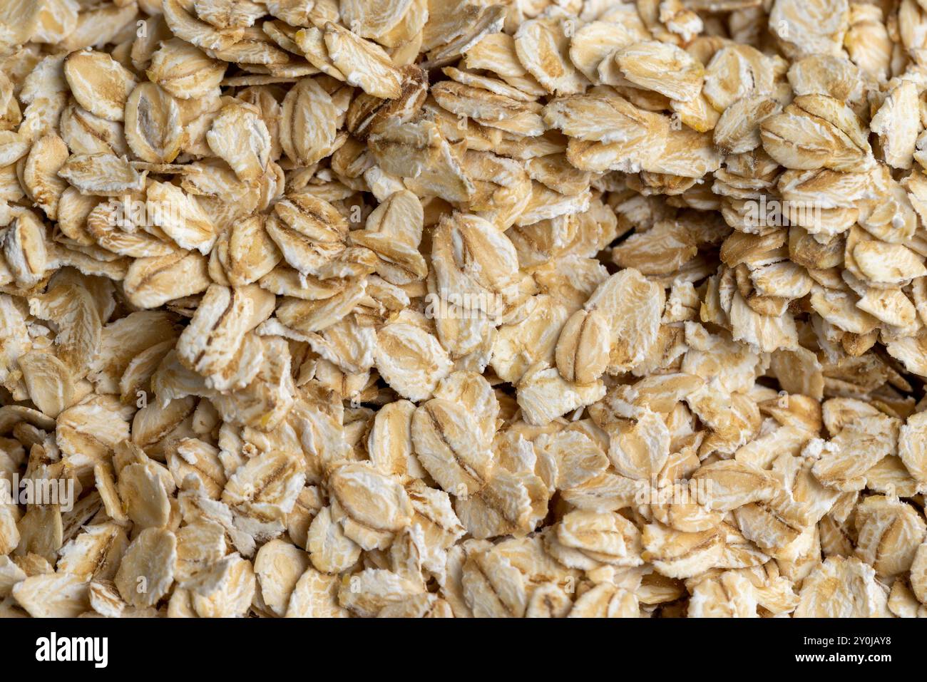 Versò una grande quantità di fiocchi di avena primo piano, sfondo di farina d'avena cruda cruda Foto Stock