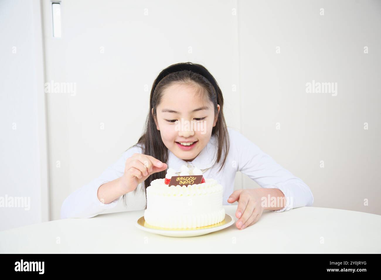Ragazza che cerca di togliere le fragole da una torta Foto Stock