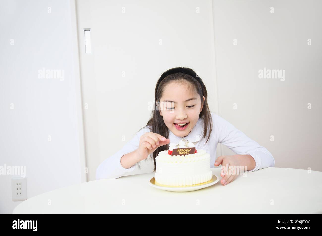 Ragazza che cerca di togliere le fragole da una torta Foto Stock