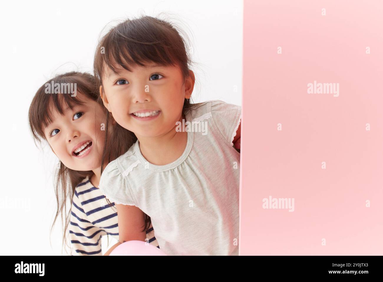 Sorelle gemelle che si presentano al muro rosa Foto Stock