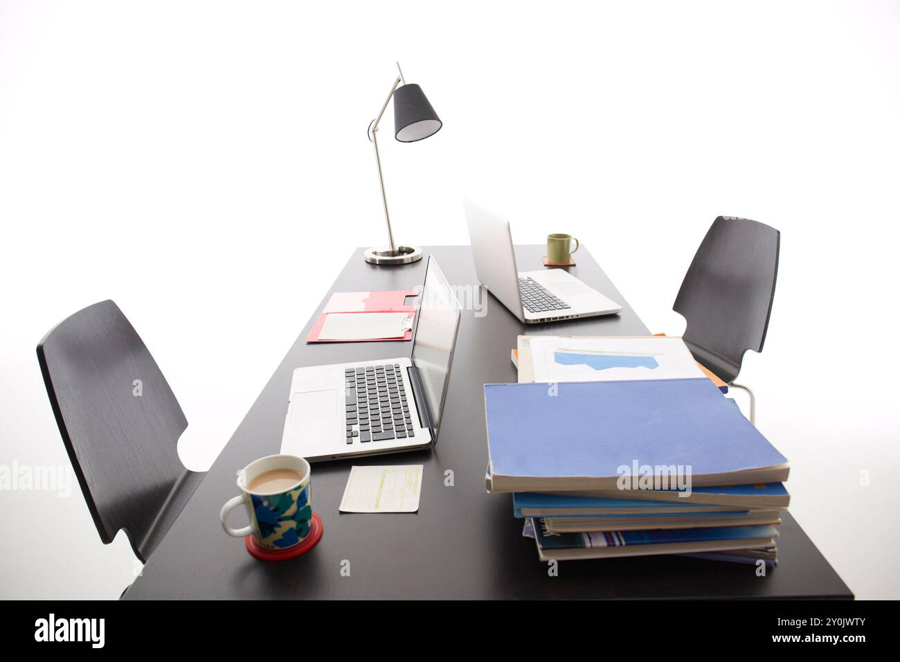 Due PC, libri, tazze da caffè e simili su una scrivania nera Foto Stock