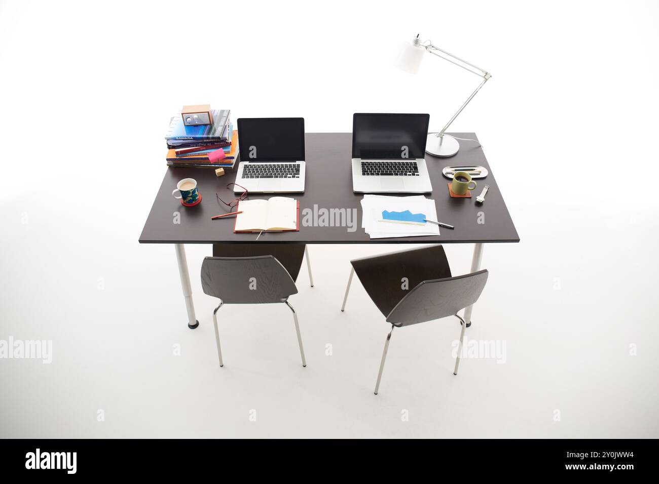 Due PC, libri, tazze da caffè e simili su una scrivania nera Foto Stock