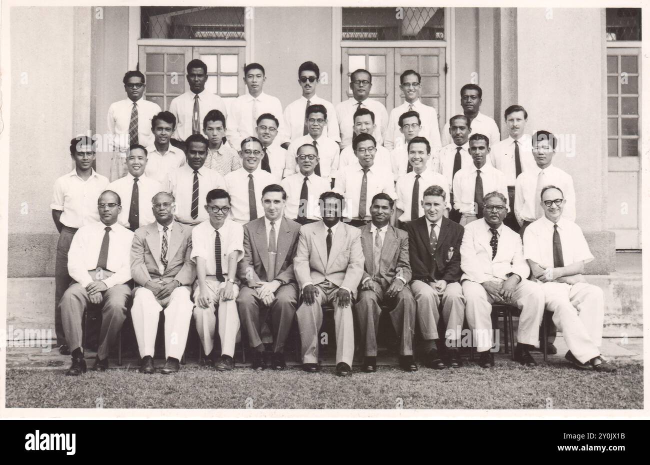Gli insegnanti della Victoria School di Singapore posano per un ritratto di gruppo a metà degli anni '1950, tra cui il signor R.G. Barker che indossa un blazer scuro in prima fila Foto Stock