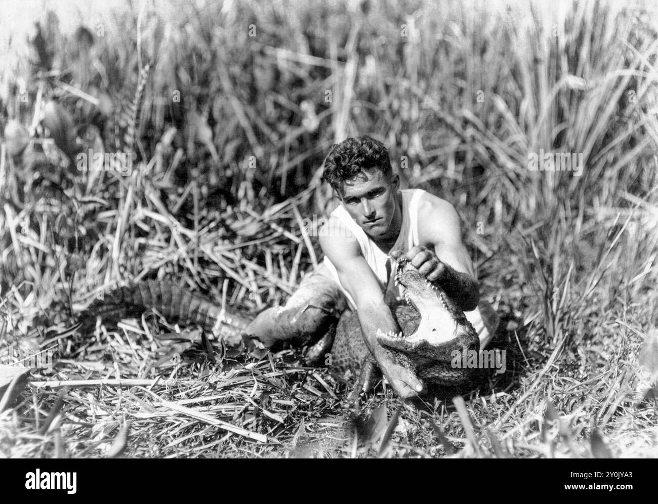 Henry Charles 'Alligator Boy' Coppinger Jr. (1898-1975) con un alligatore catturato nella zona del fiume Miami, nel sud della Florida, il 28 gennaio 1921. Coppinger "inventò" la lotta contro gli alligatori e la insegnò agli indiani Seminole che fecero il loro rituale come attrazione per i turisti all'inizio del XX secolo. (USA) Foto Stock