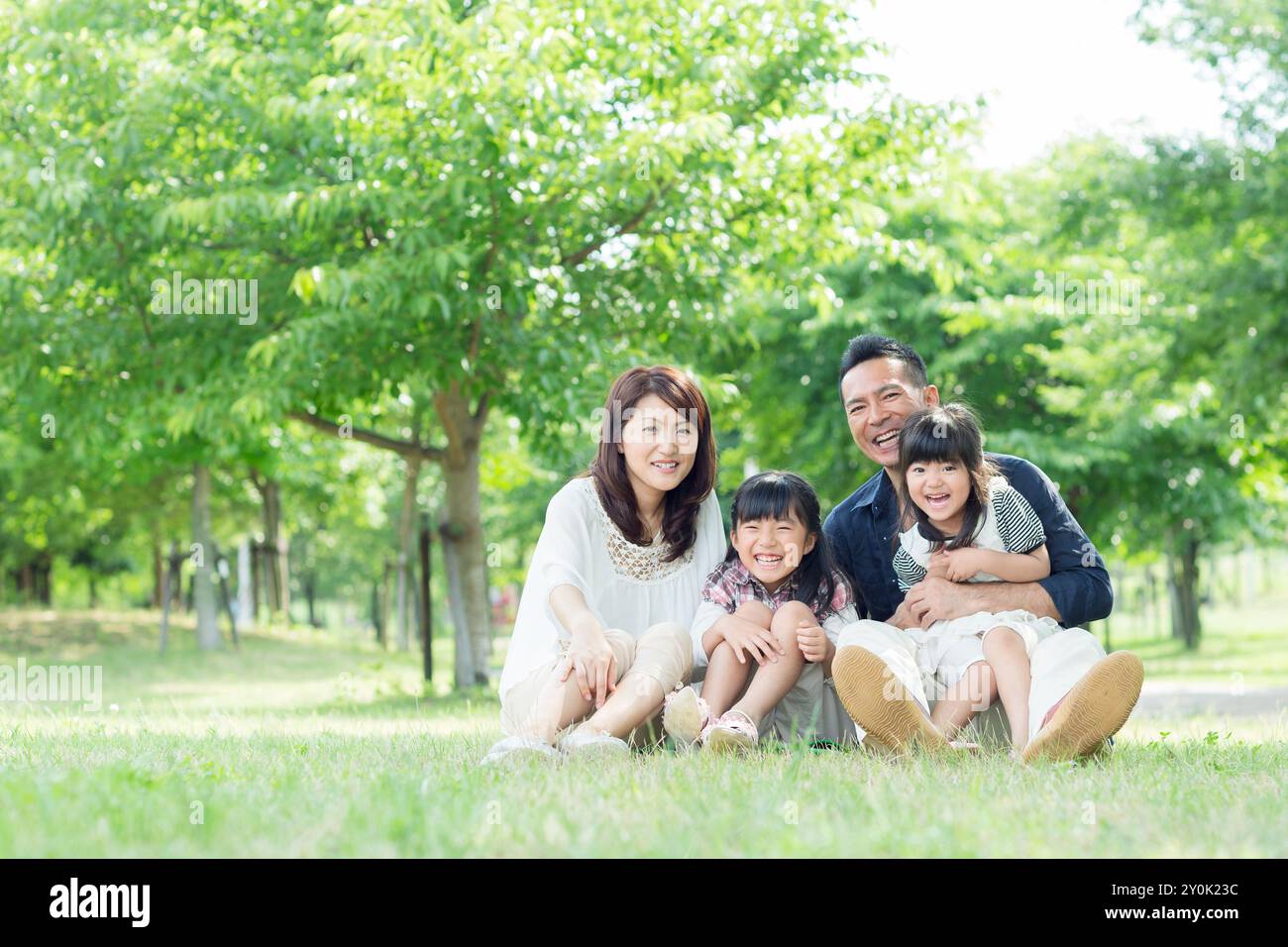 Famiglia giapponese seduta nel parco con foglie verdi fresche Foto Stock
