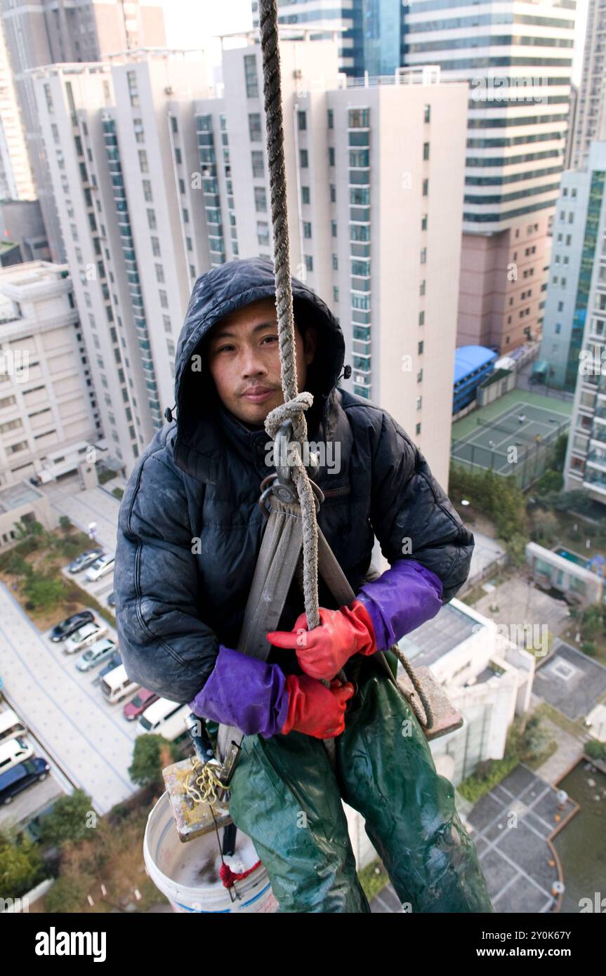 Le finestre di accesso a corda puliscono le finestre di un alto edificio a Nanchino, Cina. Foto Stock