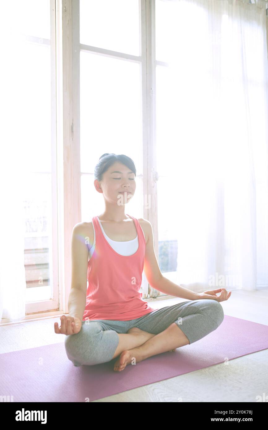 Donna che pratica yoga alla finestra Foto Stock