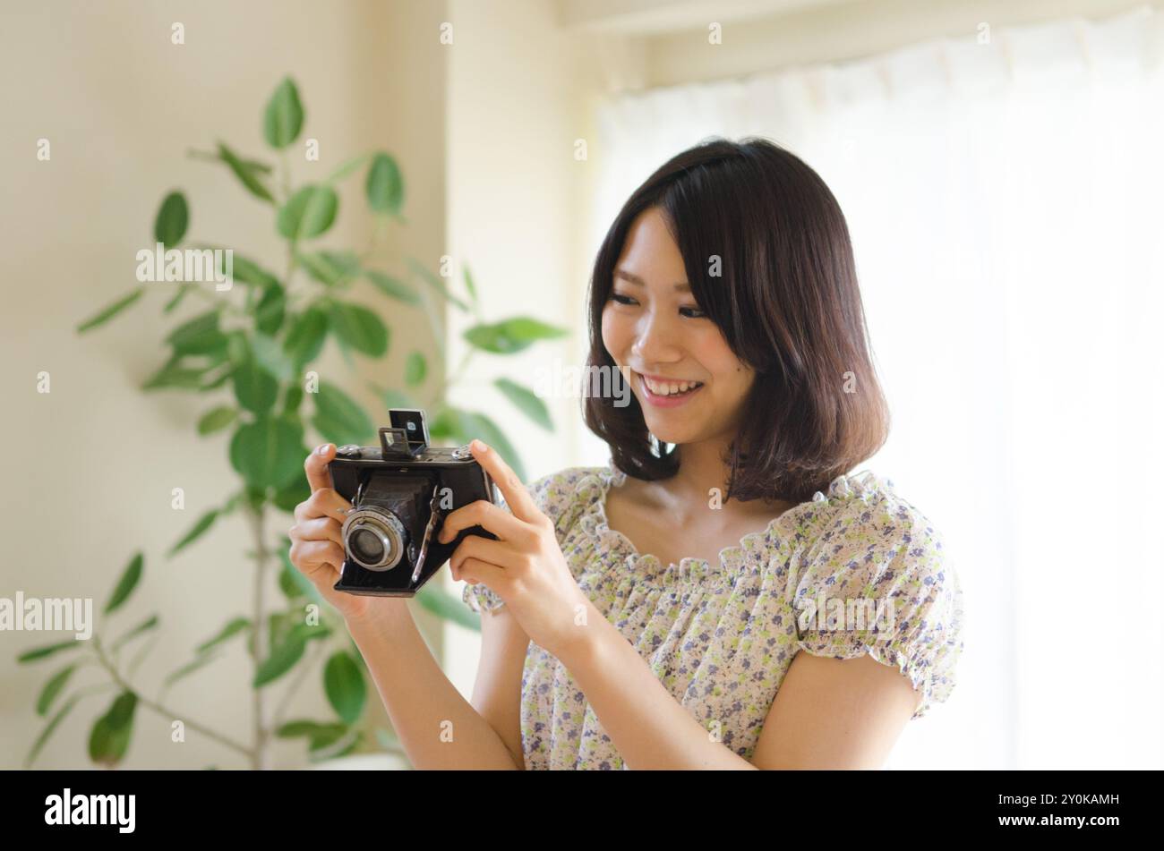 Donna sorridente che guarda una macchina fotografica d'epoca Foto Stock